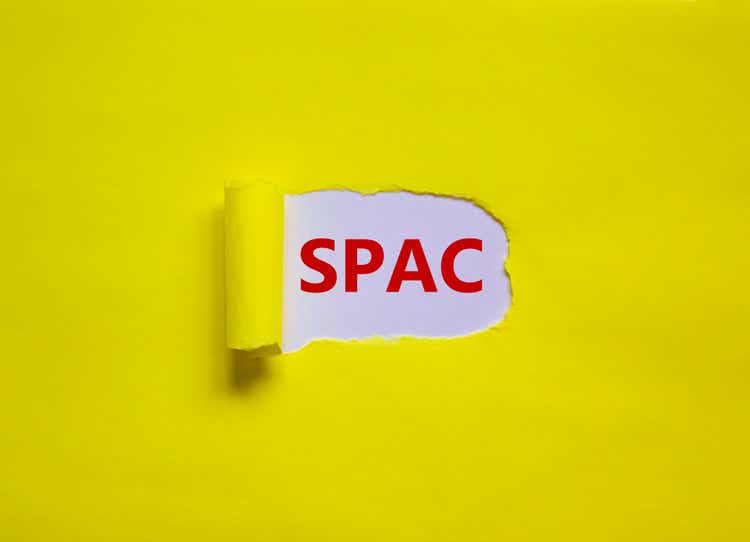 SPAC, special purpose acquisition company symbol. Words "SPAC" appearing behind torn yellow paper. Beautiful background, copy space. Business and SPAC, special purpose acquisition company concept.