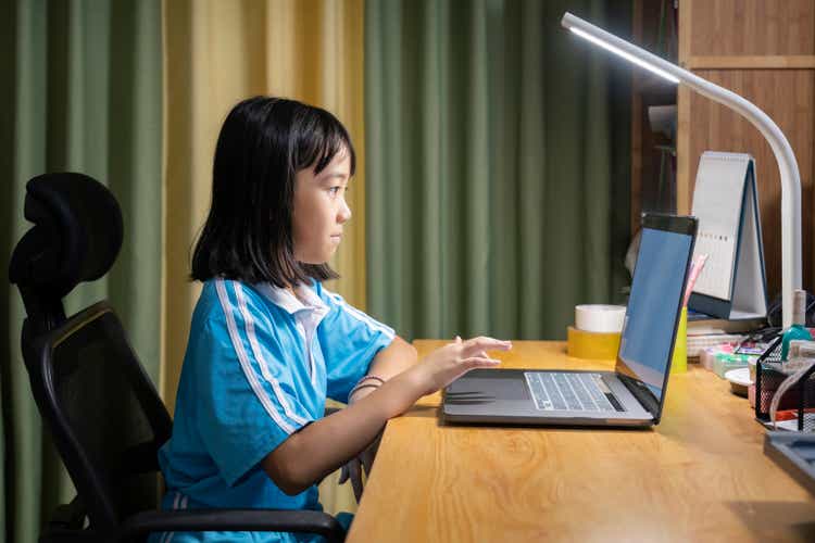 Asian little girl using laptop happily in the study at home