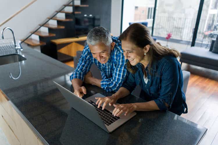 Couple at home paying bills online on their laptop computer
