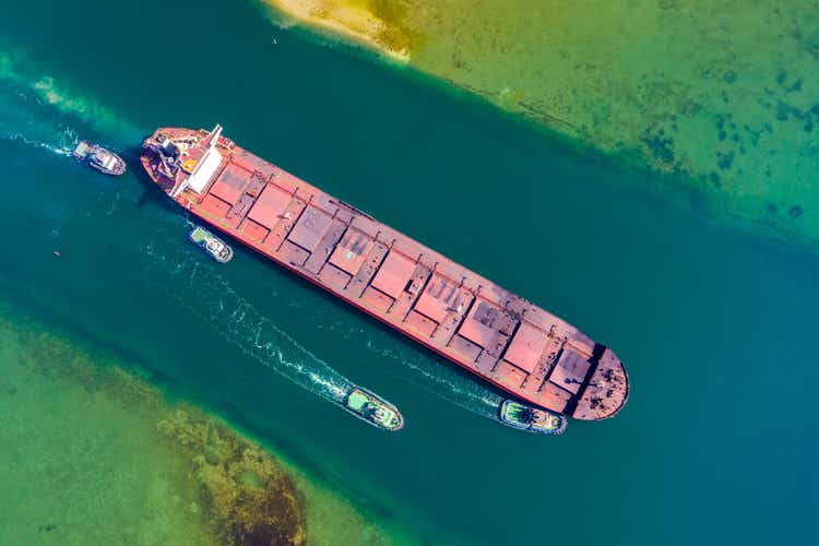 Tugs carry out pilotage of a merchant vessel of the capsaz type through the approach channel in the seaport.