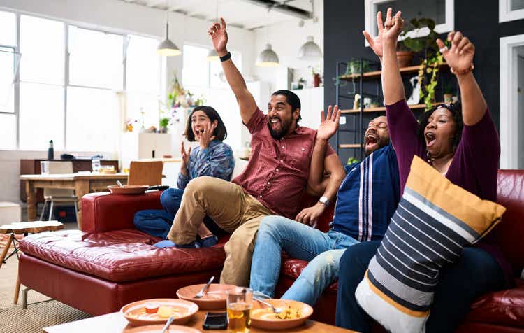 Four friends watching sport on TV and cheering