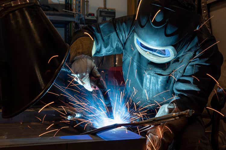 Industrial steel welder in factory. welder with protective mask welding metal and sparks