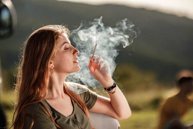 Young redhead woman smoking a cigarette in nature.