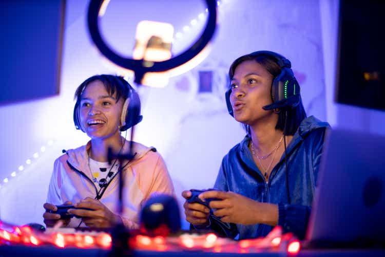 Two young black female gamers playing at night