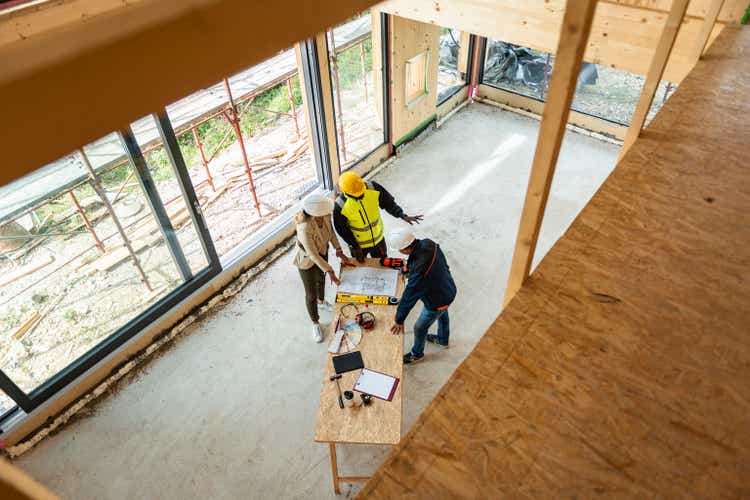 Grupo de arquitectos corrigiendo un plan de construcción en obra