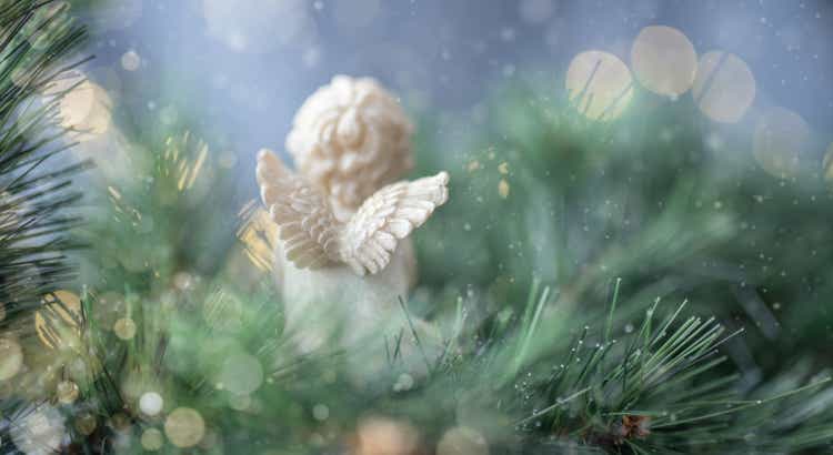 back view of angel praying on christmas tree background and golden lights