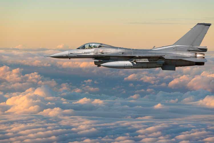 F-16 Figher jet flying above clouds at sunset