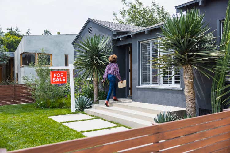 Female real estate agent carrying document while walking into house