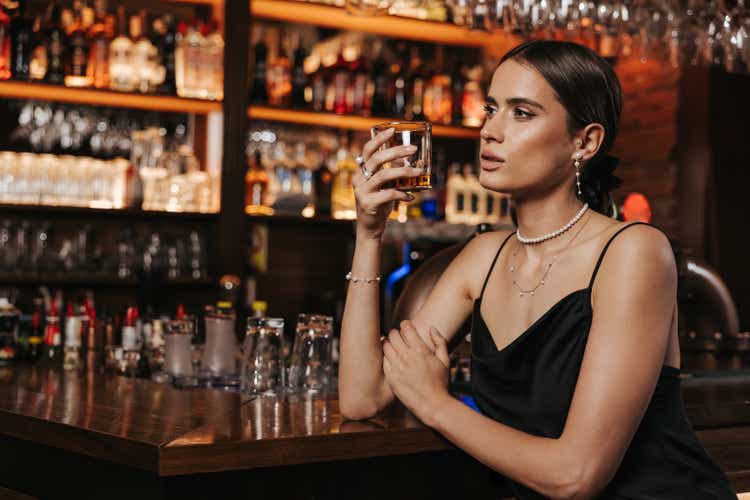Attractive young woman enjoying glass of whiskey in city club