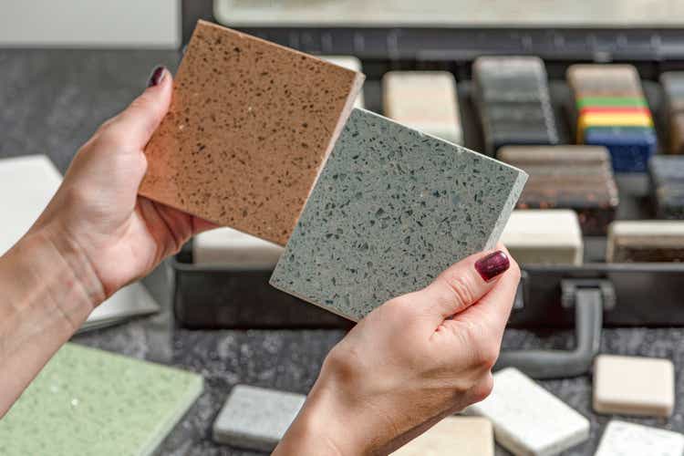 Choice of tiles. Female hands hold samples of tiles of different colors. Woman in store chooses bathroom tiles