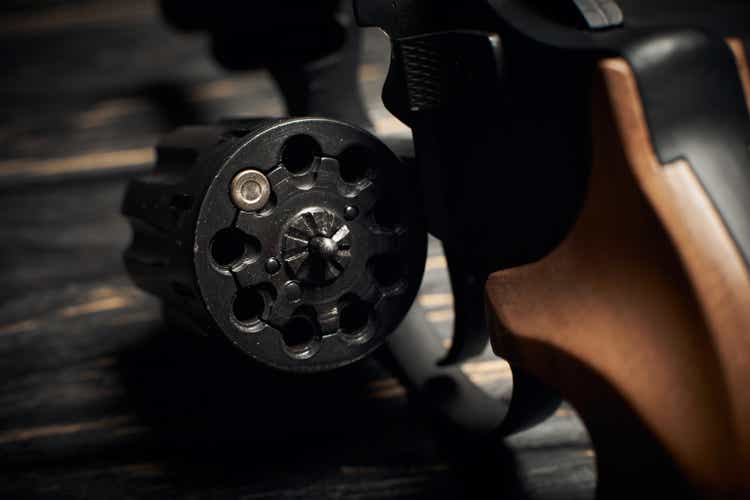 revolver cylinder with one Flobert ammo 4mm on dark wooden background. Russian roulette concept
