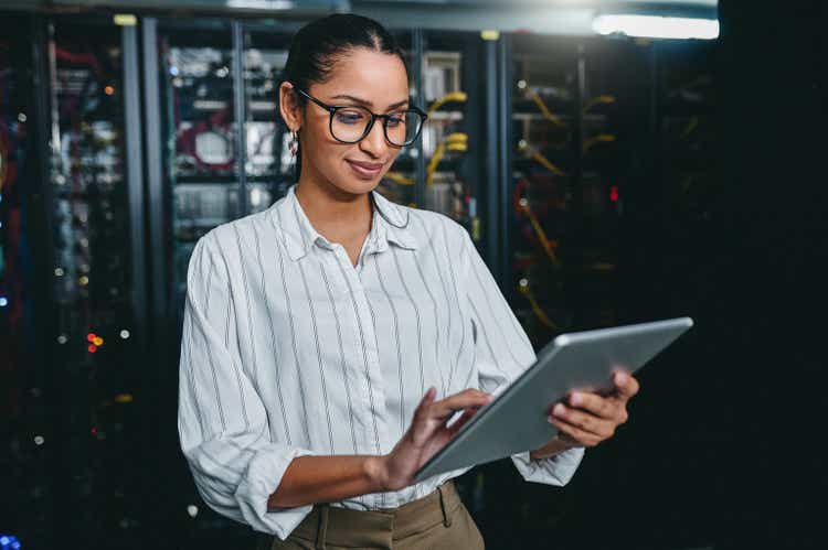 Shot of a young woman using a digital tablet while working in a server room