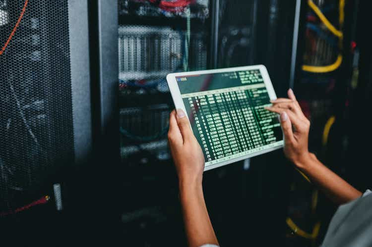 Shot of a young woman using a digital tablet while working in a server room