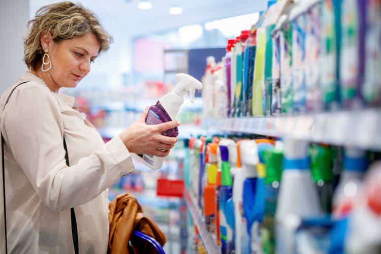 Woman choosing household detergents on supermarket shelves