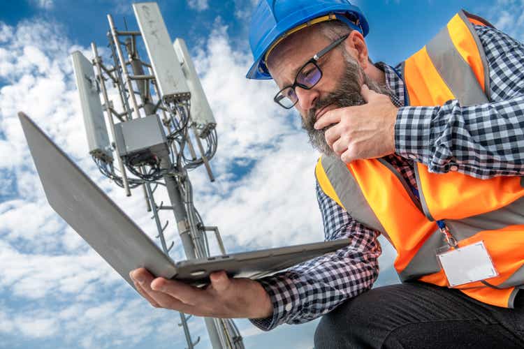 Telecommunication technician working on laptop outdoors