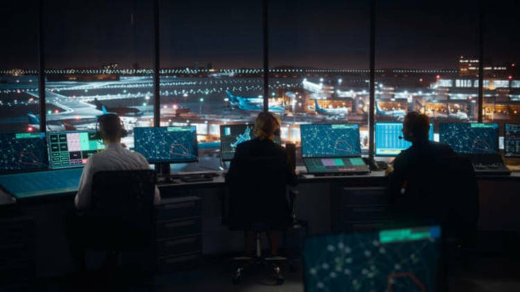 Diverse Air Traffic Control Team Working in a Modern Airport Tower at Night. Office Room is Full of Desktop Computer Displays with Navigation Screens, Airplane Flight Radar Data for Controllers.