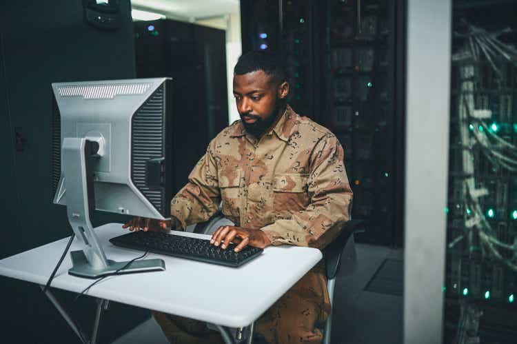 Shot of a male IT technician in a server room and using a laptop