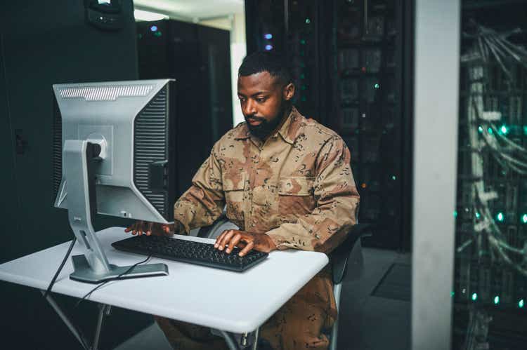 Shot of an male IT technician in a server room and using a laptop