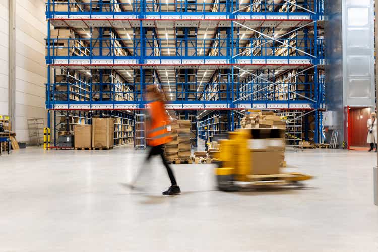 Motion blur of an employee moving boxes in warehouse