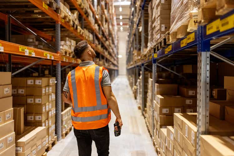 Workers wearing reflective vests work in the warehouse