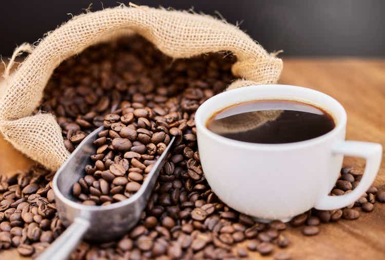 Chupito de granos de café y una taza de café negro sobre una mesa de madera