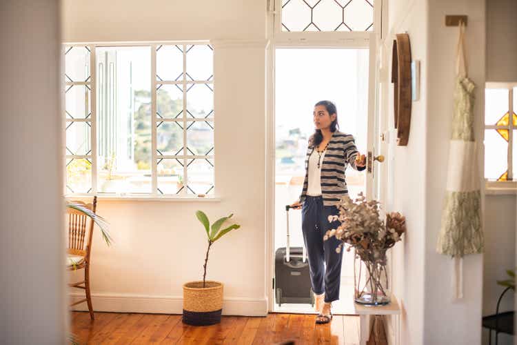 Young woman with a suitcase arriving at her vacation rental accommodation