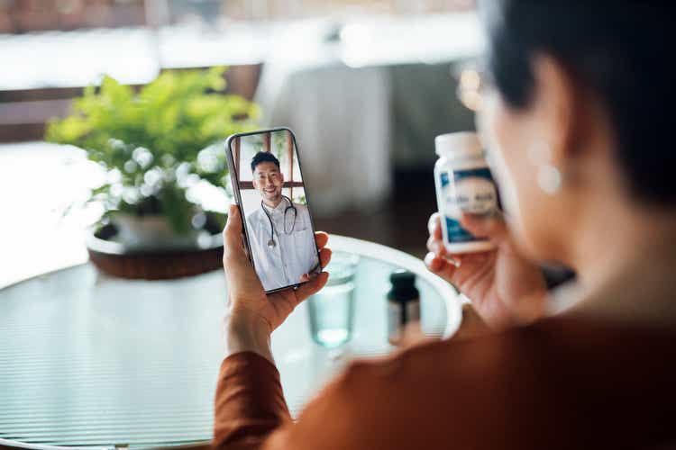 Senior Asian woman having a virtual appointment with doctor online, consulting her prescription and choice of medication on smartphone at home. Telemedicine, elderly and healthcare concept