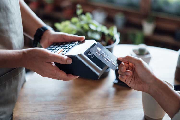 Close up of a woman"s hand paying bill with credit card in a cafe, scanning on a card machine. Electronic payment. Banking and technology