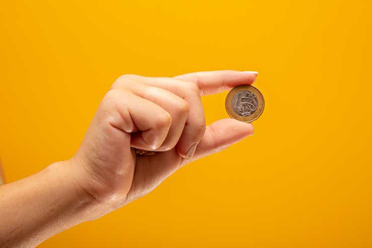 Hand holding one Real coin of Brazil