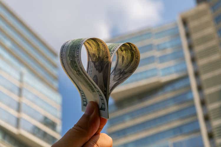 Two hundred American dollar bills in the form of a heart on the background of a modern building