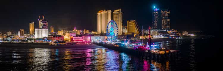 Panoramic aerial view of the Broadwalk on the waterfront in Atlantic City Downtown, the famous gambling center of the East Coast USA, with multiple casinos and amusing park with a Ferris Wheel on a pier.