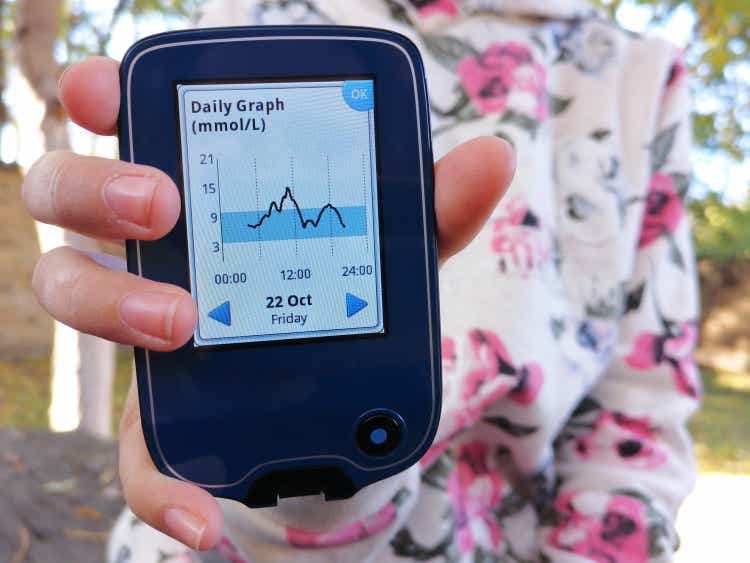 Girl with diabetes is reading the glucose levels using device for continuous glucose monitoring in blood - CGM. She shows daily graph on screen. Diabetes type 1. Insulin depend