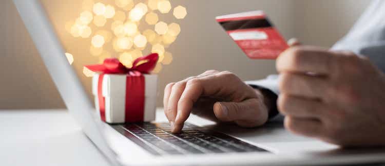 Man ordering Christmas gifts using laptop and credit card. Online shopping during holidays