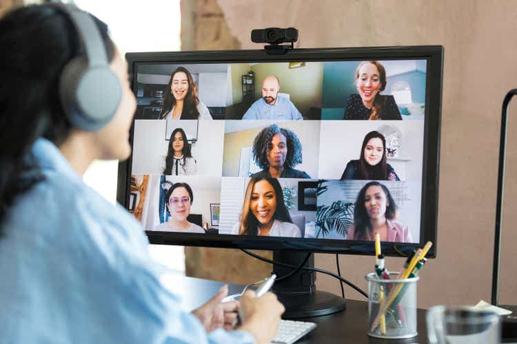 Unrecognizable woman wears headphones while attending meeting with co-workers