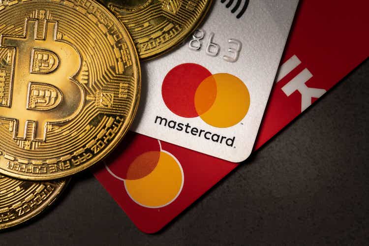 Bitcoin cryptocurrency standing on a MasterCard credit card.