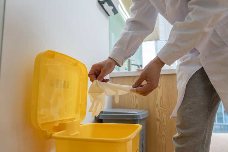 The dentist throws the disposable latex gloves into the corresponding trash can after the operation
