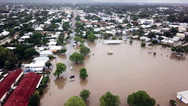 Aerial view from drone of a large flood affecting many houses in a dormitory town, where several streets are full of water, many cars and motorcycles affected, trees and parks.Probable consequence of climate change.