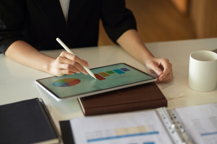 Business woman working on her financial pie chart report via digital tablet.