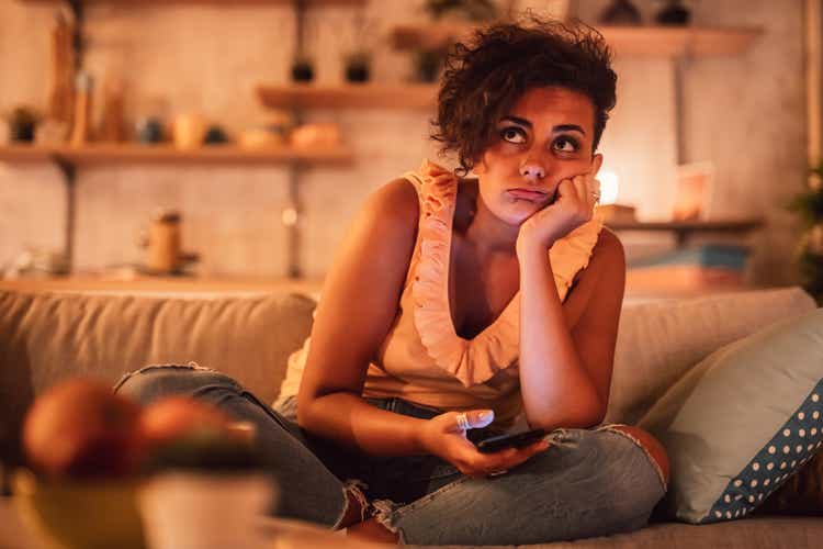Bored woman sitting on sofa and holding phone