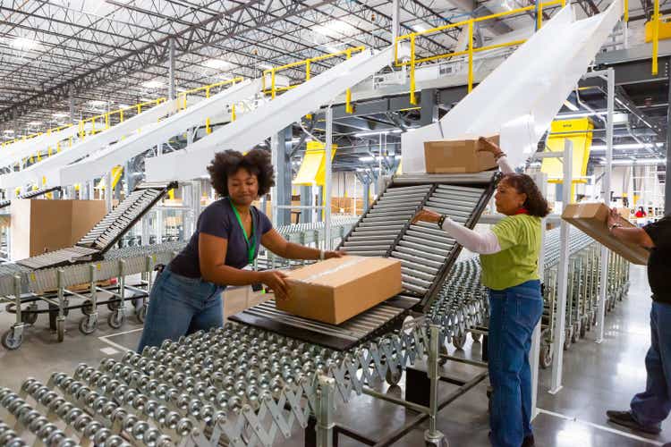 Fulfillment Center Employees Pushing Boxes Along Rollers Into Truck