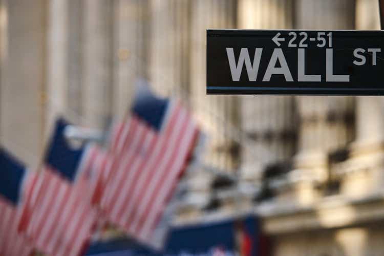 Wall Street sign post in front of Stock Exchange building in New York, USA