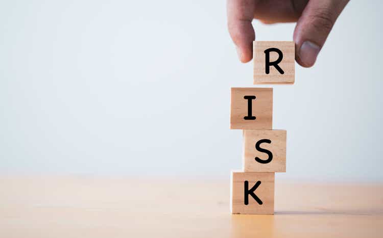 Hand putting and stacking wooden cube block of risk wording for risk management concept.
