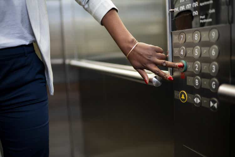 African businesswoman pressing ground floor in elevator