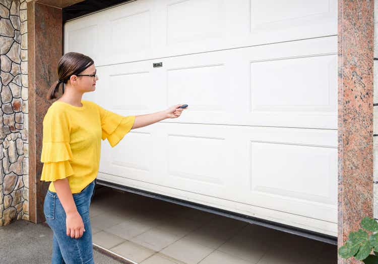 Girl or young woman holds remote controller for closing and opening garage door