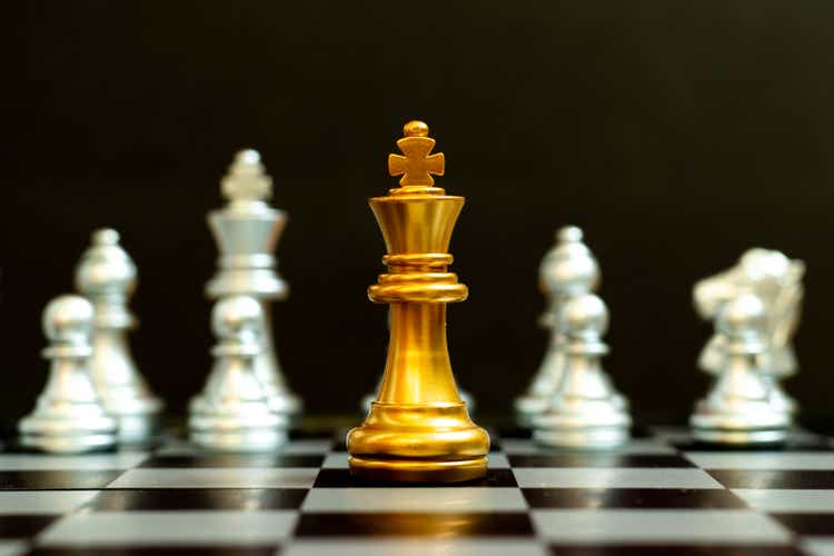 Gold king in chess game face with the another silver team on black background (Concept for company strategy, business victory or decision)