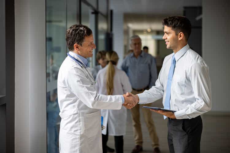 Medical sales representative greeting a doctor with a handshake at the hospital