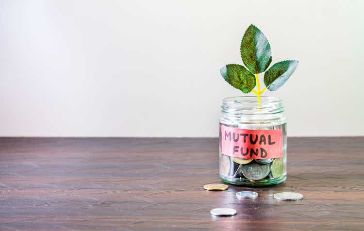 A glass jar full of coins and a plant growing through it. Concept image showing investing in Mutual Funds can help building wealth.