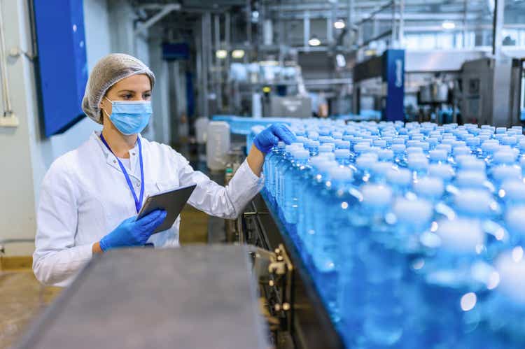 Technologist in bottling factory checking water bottles before shipment.
