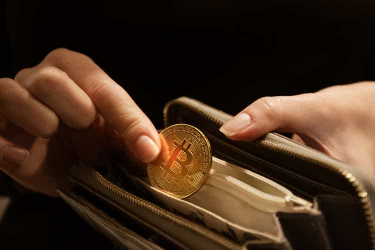 Woman puts gold bitcoin coin in her purse, close up hands shot