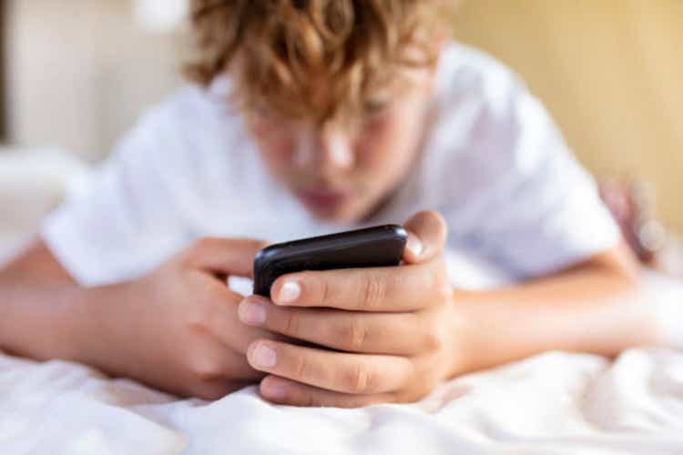 teenager boy is using smartphone at home in bed